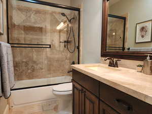 Bathroom featuring vanity and shower / bath combination with glass door
