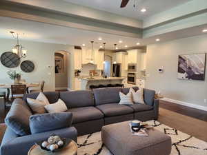Living area with wood finished floors, a chandelier, ceiling fan, and arched walkways