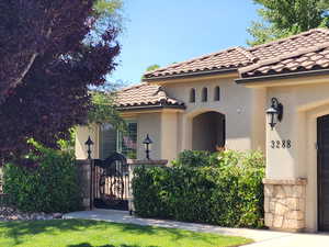 View of front facade with a gate, stucco siding, and a tiled roof