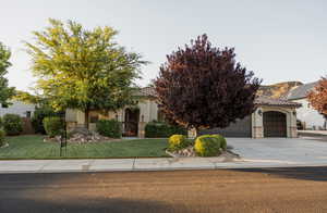 View of property hidden behind natural elements with an attached garage, stone siding, a tiled roof, driveway, and stucco siding