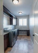 Laundry area with cabinet space, washing machine and dryer, and light tile patterned floors