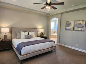 Carpeted bedroom with arched walkways, ensuite bathroom, and a ceiling fan