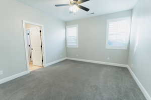 Empty room featuring light colored carpet and a ceiling fan