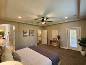 Bedroom featuring a tray ceiling, arched walkways, recessed lighting, carpet flooring, and a ceiling fan