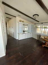 Unfurnished dining area with lofted ceiling with beams and dark wood-style flooring