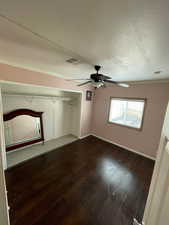 Unfurnished bedroom featuring dark wood-style flooring, ceiling fan, a textured ceiling, and a closet
