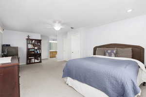 Bedroom featuring light colored carpet, ensuite bathroom, and ceiling fan