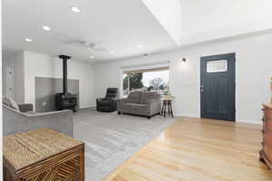 Living area with a wood stove, light wood-style floors, ceiling fan, and recessed lighting