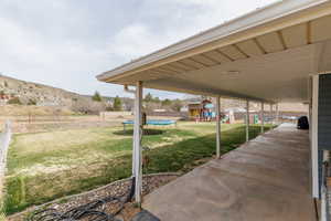 Fenced backyard with a playground, a trampoline, a mountain view, and a patio area