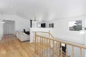 Hall with lofted ceiling, an upstairs landing, and light wood-type flooring