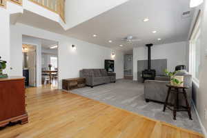 Living room featuring a wood stove, light wood-style floors, recessed lighting, and a ceiling fan