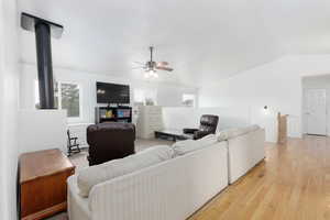 Living room with lofted ceiling, light wood-style flooring, and ceiling fan