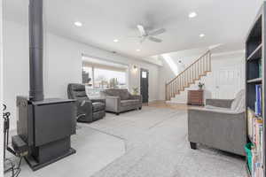Living area with ceiling fan, recessed lighting, and a wood stove