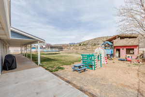 View of yard featuring a trampoline, a patio, a mountain view, and an outdoor structure