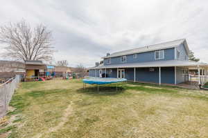 Rear view of property featuring a playground, a trampoline, a metal roof, and a patio