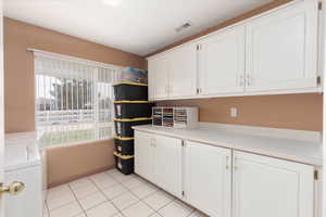 Laundry room with cabinet space, washing machine and clothes dryer, and light tile patterned floors