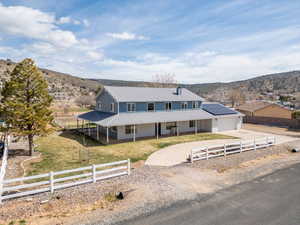 Farmhouse-style home featuring a fenced front yard, concrete driveway, a mountain view, and a metal roof