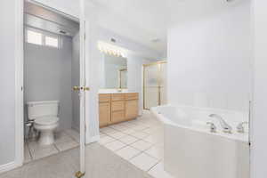 Full bath with a shower stall, vanity, a garden tub, and light tile patterned floors