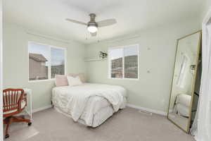 Bedroom with ceiling fan and light colored carpet