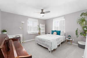 Bedroom with a ceiling fan, light carpet, and multiple windows