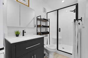 Full bath with vanity, a stall shower, and stacked washer/dryer