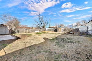 fenced yard with storage and garden beds