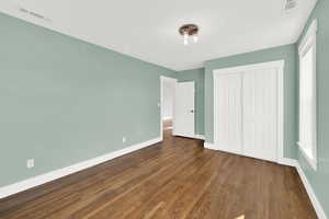 Bedroom with closet and hardwood flooring, this room has pull down blinds.