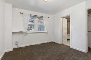 Unfurnished bedroom with dark colored carpet and a walk in closet