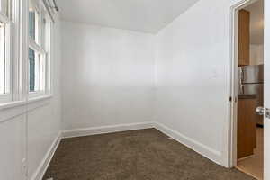 Empty room featuring dark colored carpet and baseboards