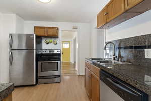 Kitchen featuring stainless steel appliances, light wood-style floors, wood finish cabinetry, and tile countertops