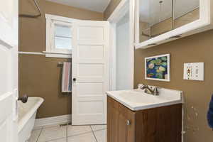 Full bathroom with a freestanding tub, vanity, and light tile patterned floors