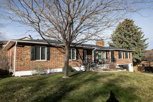 Single story home featuring brick siding, a front yard, a chimney, and a garage