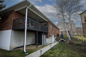 View of side of property with a patio, brick siding, and a balcony