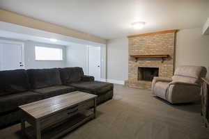Carpeted living area featuring a brick fireplace and baseboards
