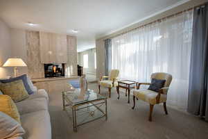 Living room featuring light colored carpet, a multi sided fireplace, and a textured ceiling