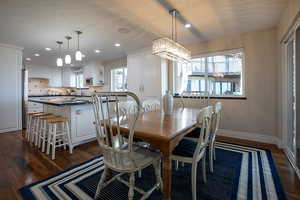 Dining area with dark wood-style flooring, hanging lights, and a textured ceiling