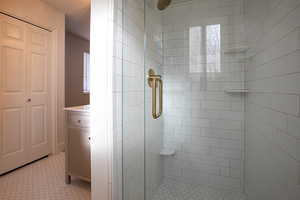 Bathroom featuring a shower stall, a closet, vanity, and plenty of natural light