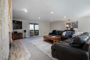Living area with carpet floors, a textured ceiling, and recessed lighting