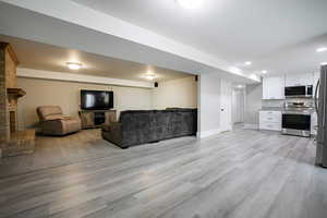 Living room featuring recessed lighting, light wood-type flooring, and a fireplace