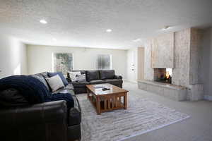 Carpeted living area featuring a multi sided fireplace and a textured ceiling