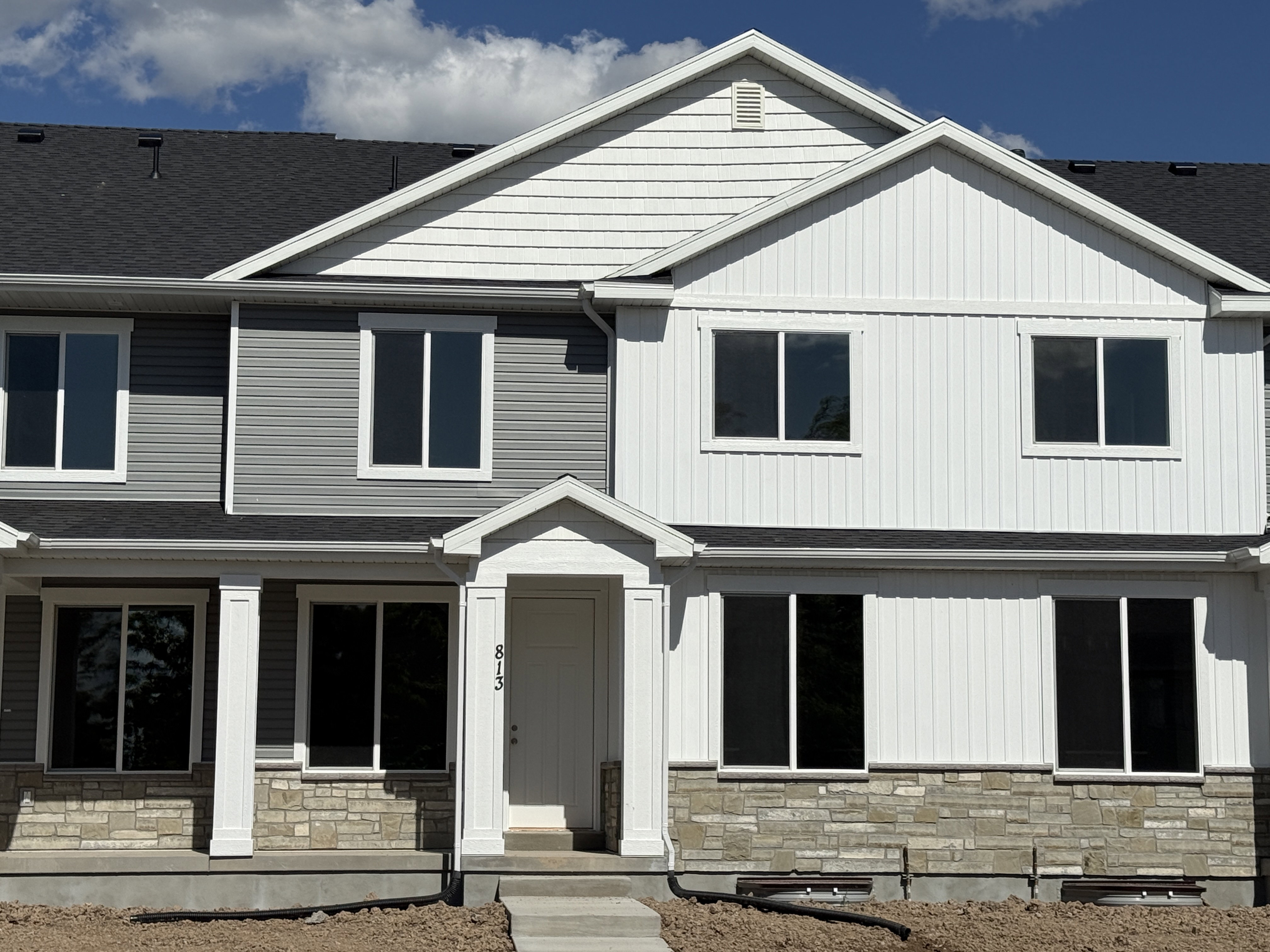 Contemporary facade featuring a mix of horizontal and vertical siding, stone accents, and an inviting covered entry