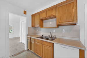 Kitchen with dishwasher, light countertops, tasteful backsplash, and light colored carpet