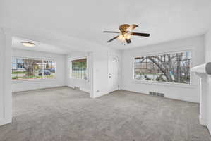 Unfurnished living room with light colored carpet and a ceiling fan