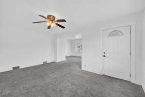 Carpeted entryway with a ceiling fan and baseboards