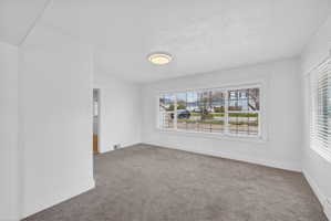 Carpeted spare room featuring baseboards