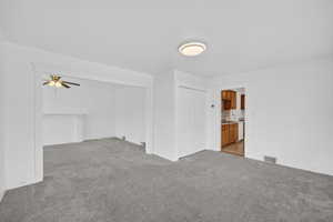 Unfurnished living room with light carpet and a ceiling fan