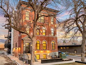 Back of house at dusk featuring brick siding and stairway