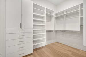 Walk in closet with light wood-style floors
