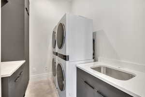 Laundry room featuring light tile patterned floors and stacked washer and dryer