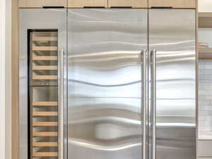 Kitchen featuring stainless steel built in refrigerator, wine cooler, light wood-style flooring, light stone counters, and tasteful backsplash